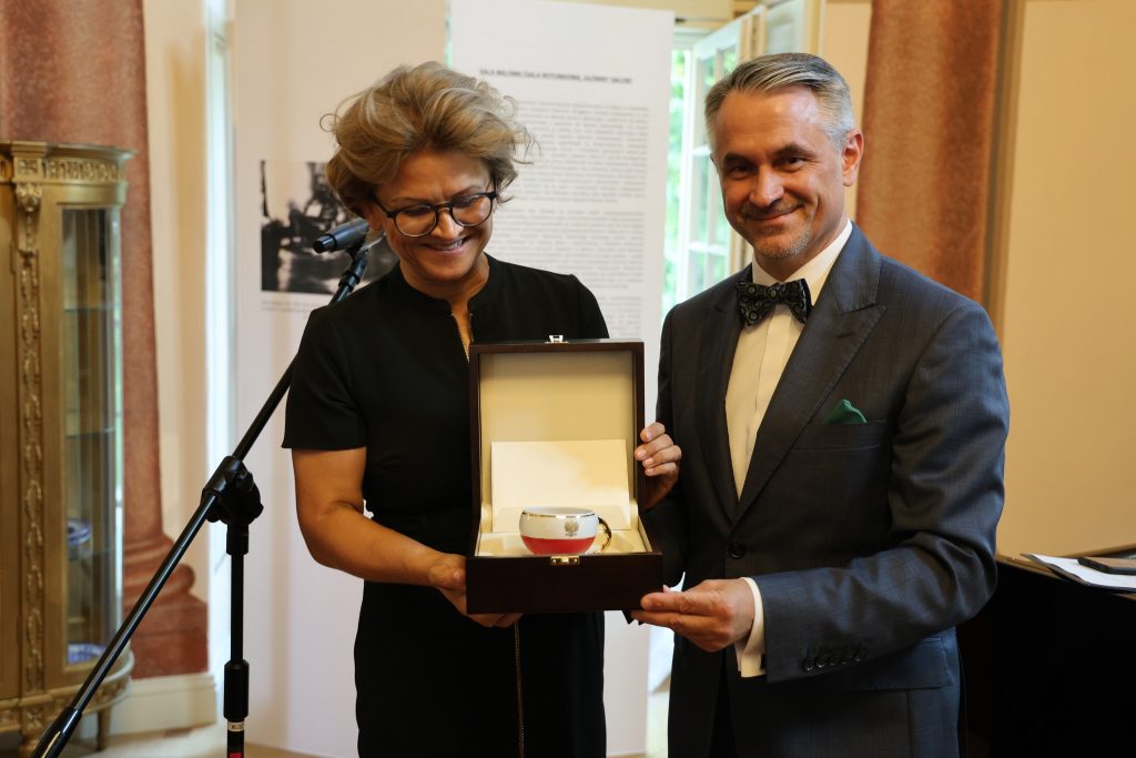 Dyrektor Sylwia Nowicka z Ambasadorem Polski w Berlinie Dariuszem Pawłosiem, który wręcza dyrektor biało-czerwoną filiżankę