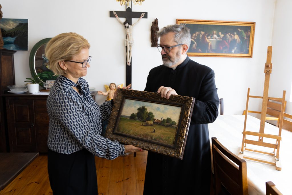Ksiądz kanonik Roman Krzyżaniak przekazujący obraz dyrektor Sylwii Nowickiej